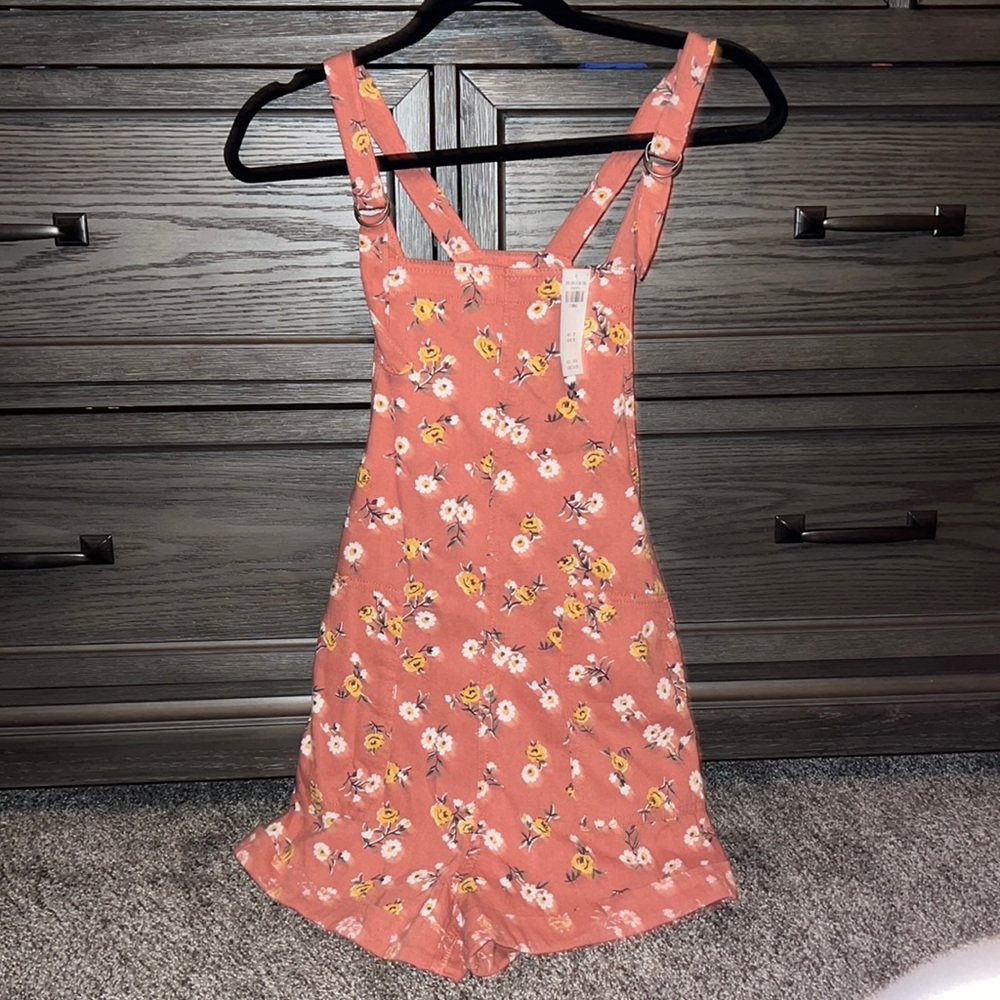 Hollister Romper with flowers. Has two pockets and buttons on sides